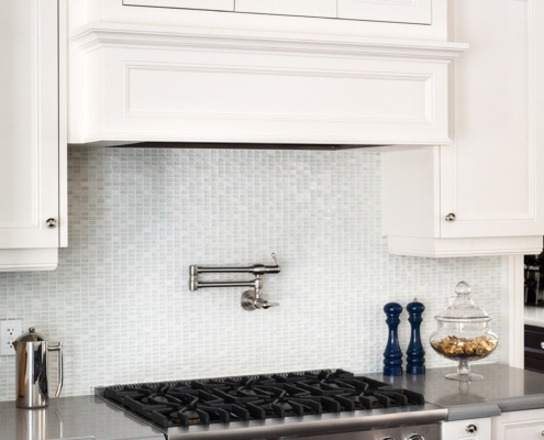 White kitchen with white countertops, tile backsplash and white cabinets.