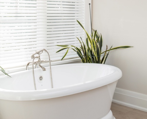 Master bathroom with tile floor, freestanding tub and white baseboard.