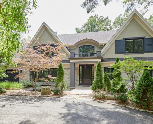 Front facade of home with stucco siding, black frame window and wood front door.