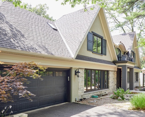 Custom home with stucco siding, natural stone and dark trim.