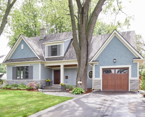 Mississauga house with wood garage door, shingled roof and white trim.