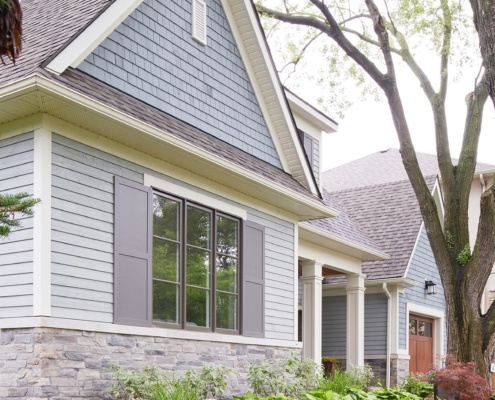 Traditional home with natural stone, gray shutters and shingled roof.