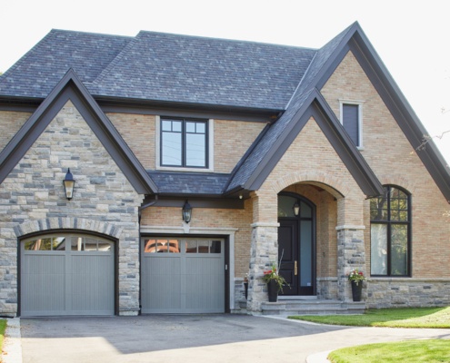Toronto custom home with natural stone siding, gables and 2 car garage.