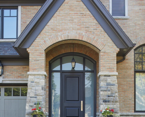 Traditional home iwth black front door, brick and dark trim.