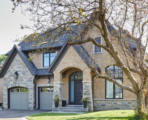 Custom home with stone siding, brick and black frame windows.