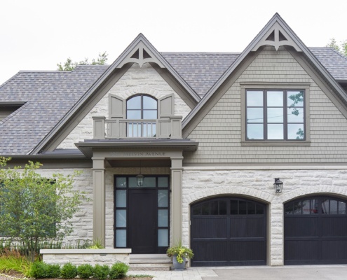 Traditional house design with wood front door, covered entry and wood siding.