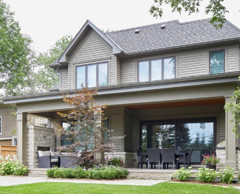 Home exterior with wood siding, covered porch and stone fireplace.
