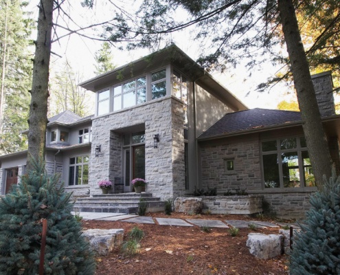 Contemporary home with corner windows, stucco siding and stone chimney.