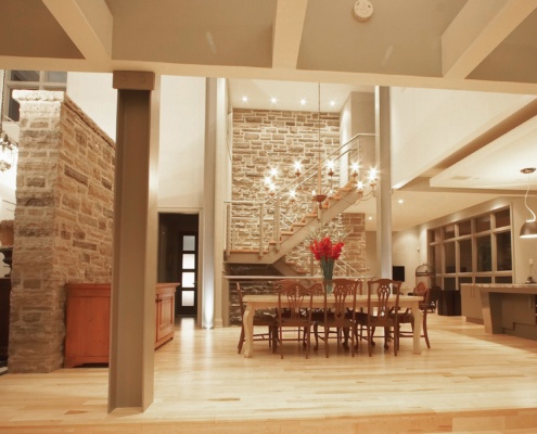 Home interior with stone wall, modern staircase and hardwood floor.