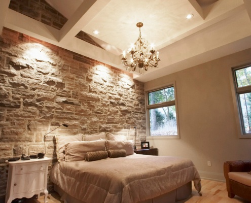 Master bedroom with stone wall, hardwood floor and white trim.