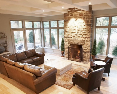Family room with stone fireplace, large windows, floating vanity and white baseboard.