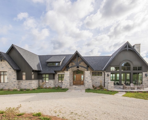 Custom home exterior with gabled roof, natural stone and circular driveway.