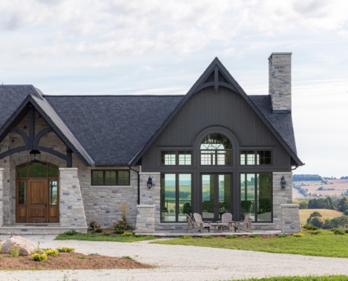 Traditional house with wood front door, shingled roof and dark trim.