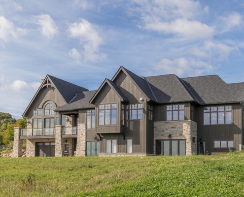 Traditional house with stone columns, wood siding and arched windows.