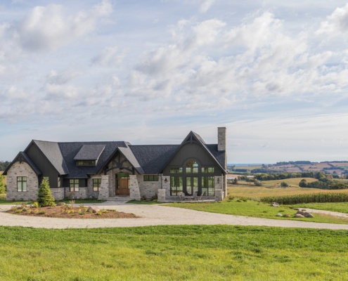 Custom home with stone siding, large portico and shingled roof.