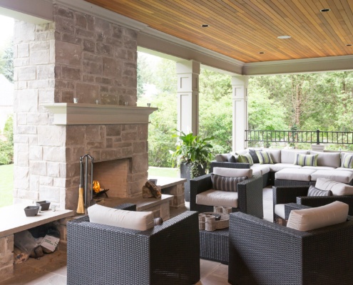 Outdoor living with stone fireplace, stucco column and stone beach.