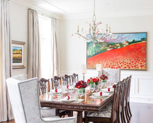 Dining room with white windows, wainscoting and chandelier.