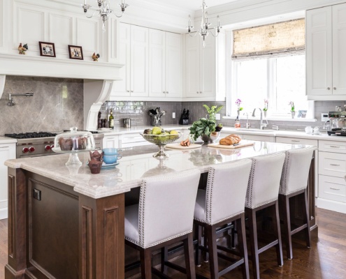 White kitchen with wood island, breakfast bar and chandelier.