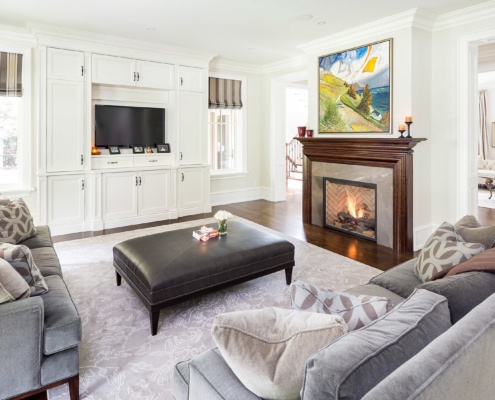 Family room with wood fireplace, white cabinets and wood floor.