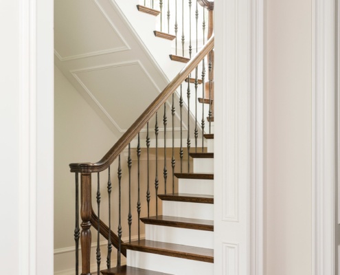Wood staircase with wood treads, hardwood floor and white trim.