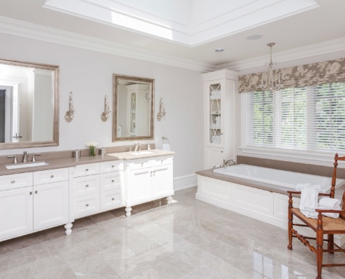 Master bathroom with tile floor, white baseboard and white cabinets.