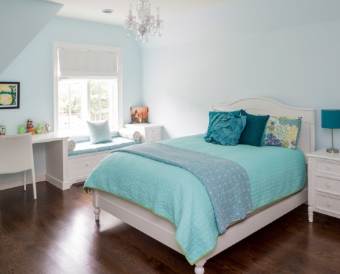 Guest bedroom with hardwood floor, white frame window and white furniture.