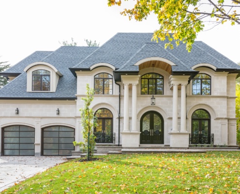 Chateau style home with black trim, light stone and glass garage door.