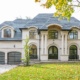 Chateau style home with black trim, light stone and glass garage door.