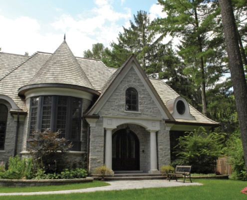 Custom home with stone columns, black frame windows and turret.