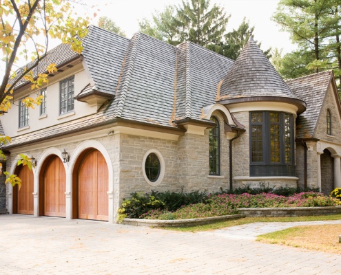 Traditional home with wood garage door, stucco siding and turret.