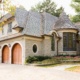 Traditional home with wood garage door, stucco siding and turret.