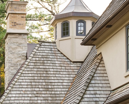 Traditional house with stone chimney, metal roof and wood shingles.