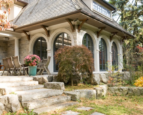 Custom home with black frame windows, stone columns and stucco siding.