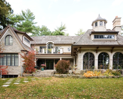 Traditional architectural design with  natural stone, second floor balcony and gabled roof.