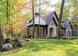 Traditional home design with natural stone, dark brown trim and large windows.