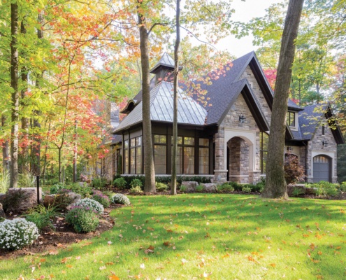 Traditional home design with natural stone, dark brown trim and large windows.