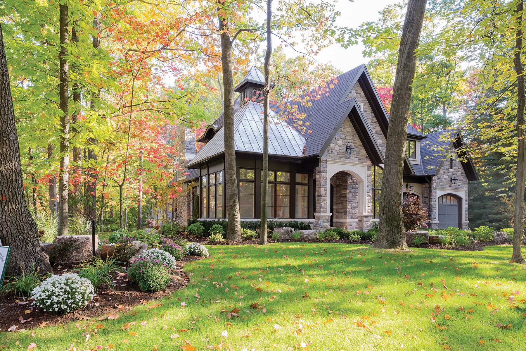 Traditional home design with natural stone, dark brown trim and large windows.