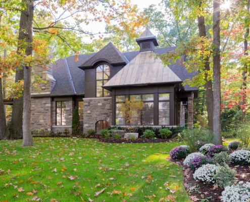 House backyard with stone chimney and shingled roof.