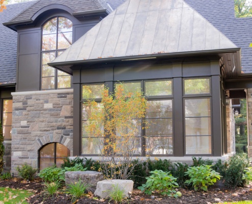 Home exterior with metal roof, cupola and arch windows.
