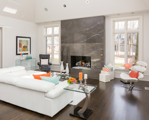 Contemporary family room with hardwood floor, white frame window and floor to ceiling fireplace.