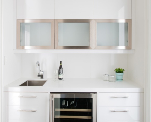 Modern servery with hardwood floor, white cabinetry and wine cooler.