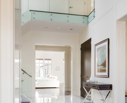 Hallway with marble floor, vaulted ceiling and glass railing.