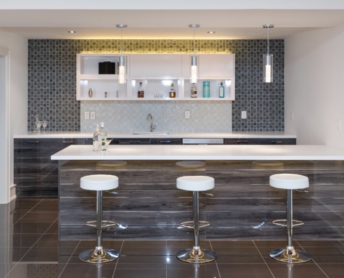 Basement bar with tile floor, granite island and tile backsplash.