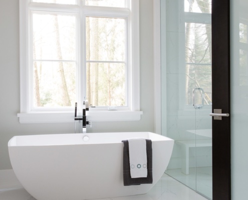 Bathroom with white frame window, marble floor and freestanding tub.