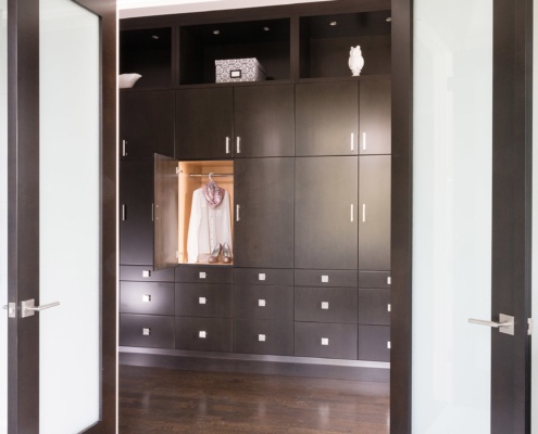 Dressing room with dark cabinetry, hard wood floor and double doors.