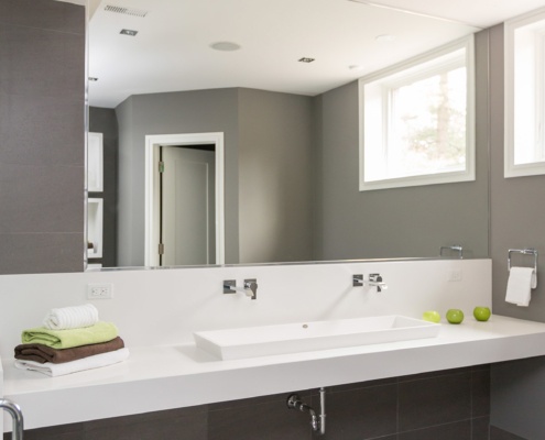 Modern bathroom with double sink, full length mirror and grey tile.