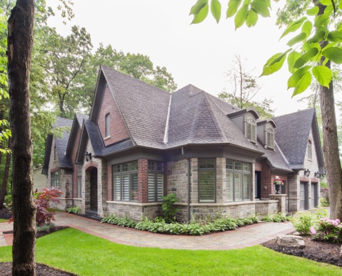 Custom home with gables, black frame windows and stone skirt.