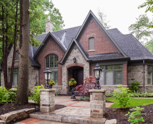 Traditional home with natural stone, red brick and dark trim.