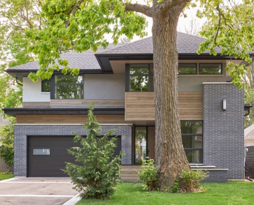 Mississauga house with black brick, landscape wall and sconce lighting.