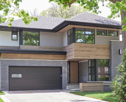 Custom house with white stucco, shingled roof and black brick.